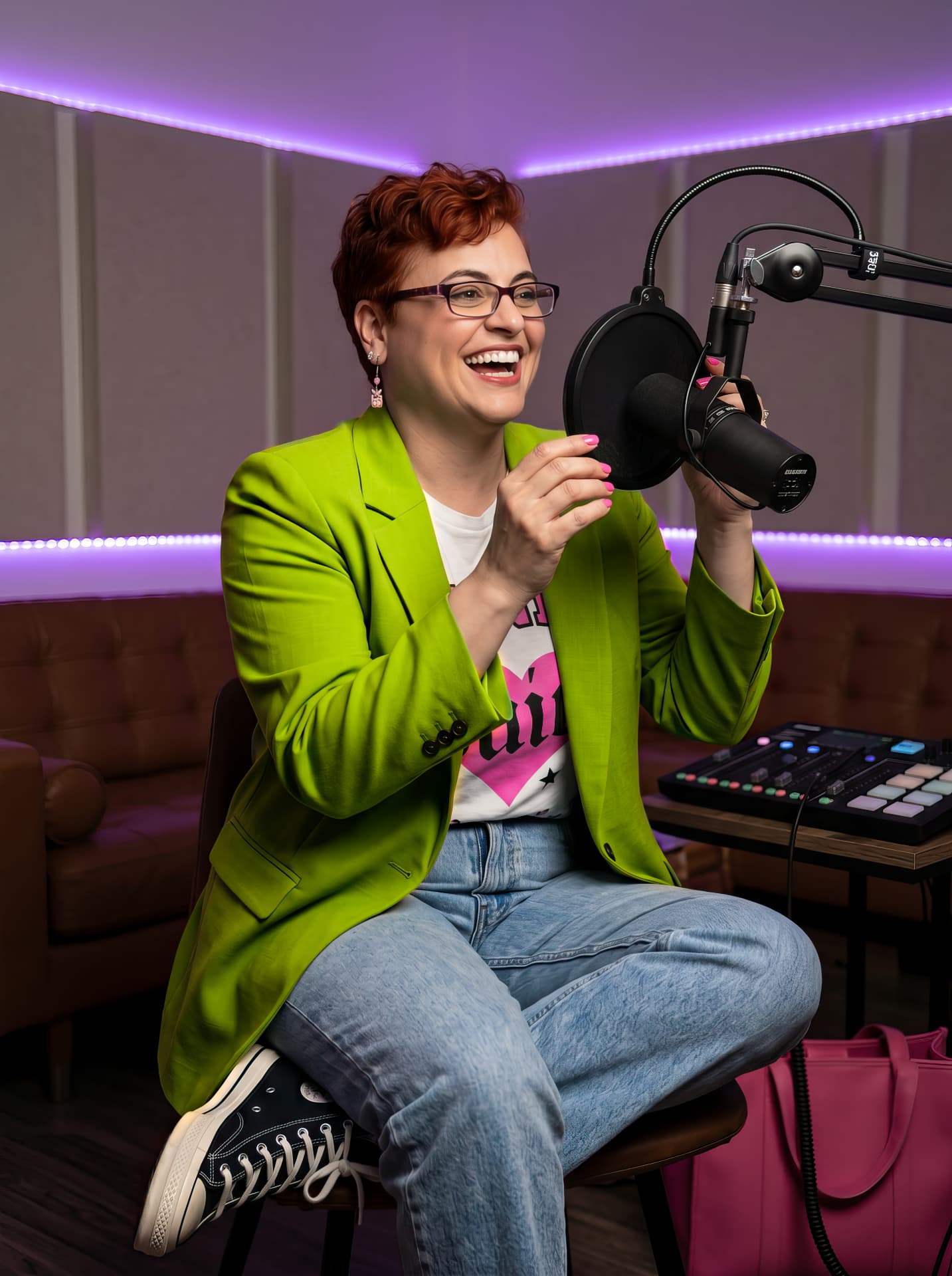 Nadia laughing at a podcast microphone in a neon-green blazer